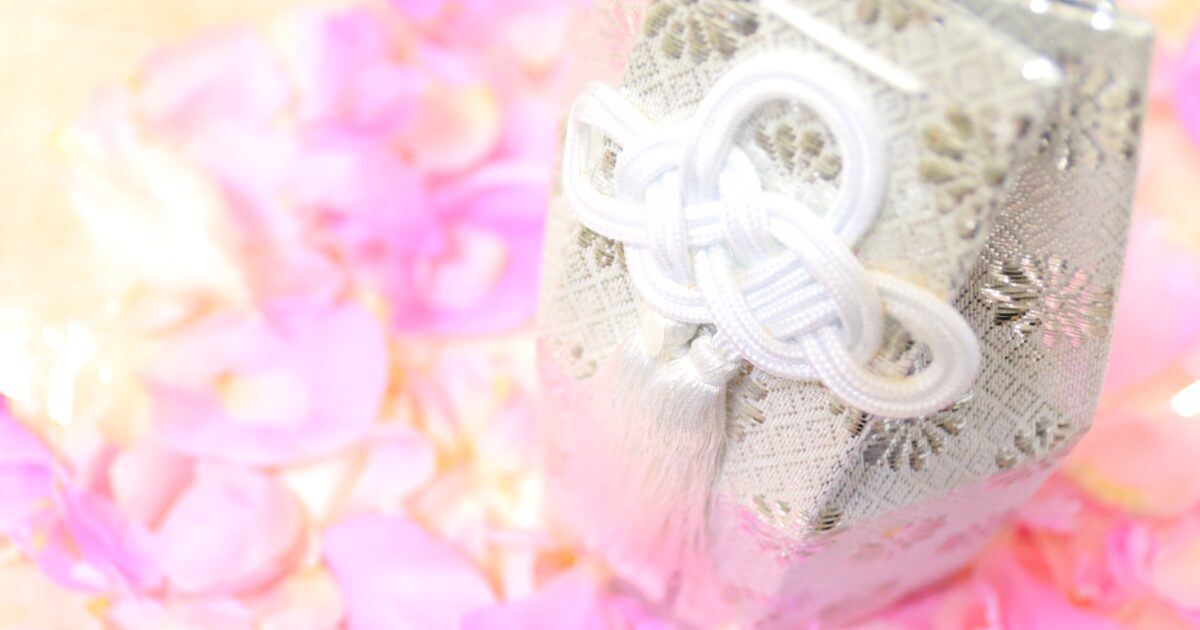 ピンクの花びらに囲まれた銀色の骨壷袋