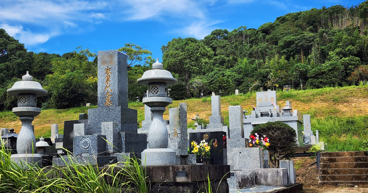緑に囲まれた墓地と並ぶ石灯籠