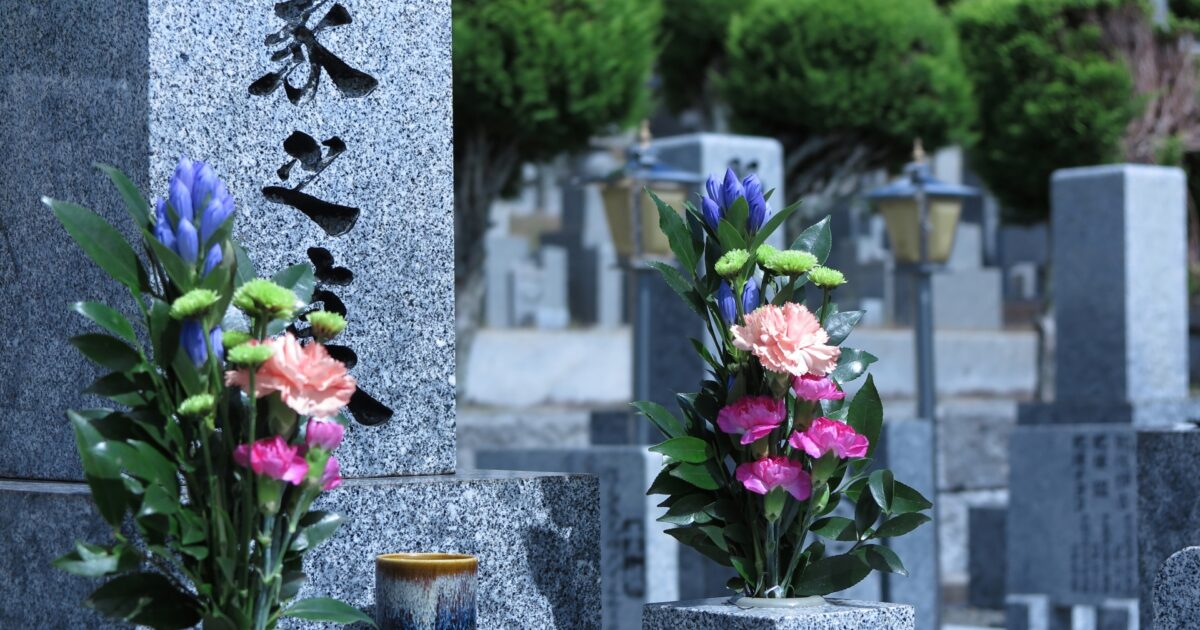 緑豊かな墓地に建つ墓石と美しく飾られた供花